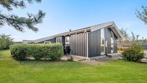 Ein modernes Haus mit Satteldach, großen Fenstern und einem gepflegten Rasen.