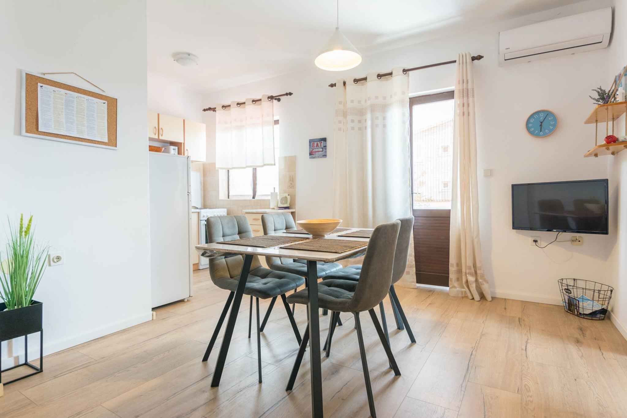 A modern kitchen with a dining area, a flat-screen TV, and a clock on the wall.