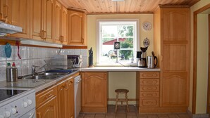 Una cocina con armarios de madera, una ventana con vistas al exterior, un reloj y una cafetera.