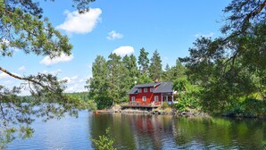 Una casa roja con un muelle sobre un lago rodeado de árboles.