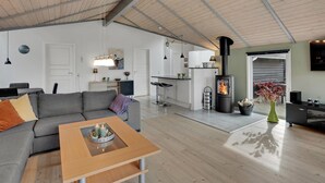 En moderne stue med en grå sofa, et træbord og et tekøkken med komfur.
