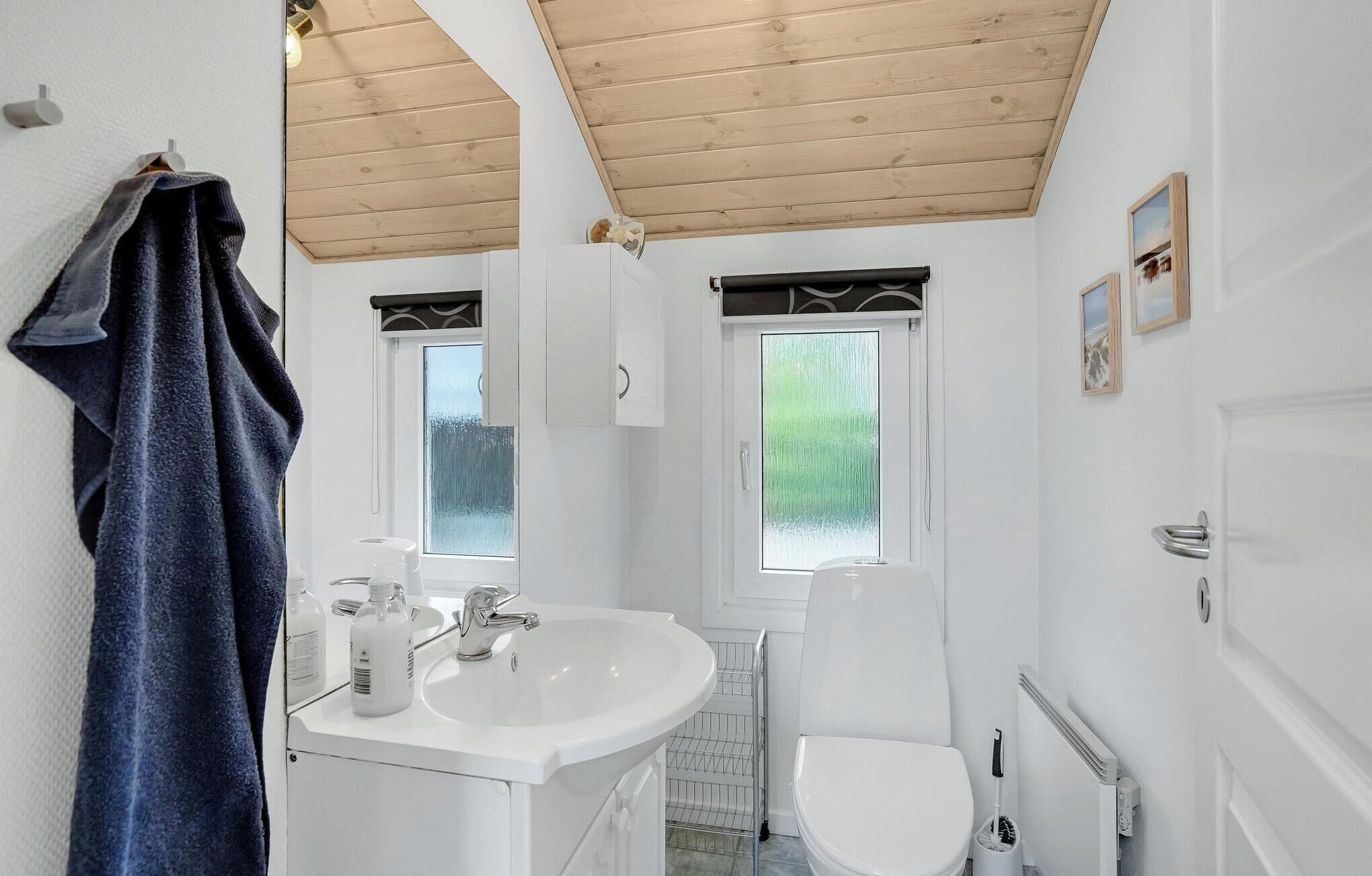 Een badkamer met een wit wastafel, een toilet en een raam met uitzicht op groen.