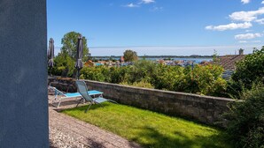 Une terrasse offrant une vue sur un plan d’eau, avec un mur en pierre et du mobilier d’extérieur.