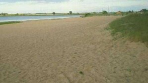 Une plage de sable avec une étendue d’eau en arrière-plan.