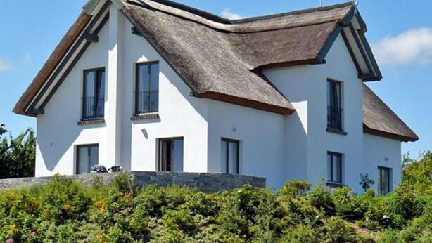 Une maison à deux étages, dotée d’un toit à forte pente, de murs extérieurs blancs et de fondations en pierre.