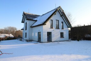 A two-story house with a steeply pitched roof, a chimney, and a small front porch.