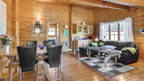 Un intérieur de chalet chaleureux comprenant un coin repas, un canapé et une cuisine.