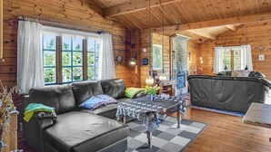 L’intérieur d’un chalet confortable, avec des murs en bois, un canapé en cuir, une table à motifs et une cheminée.