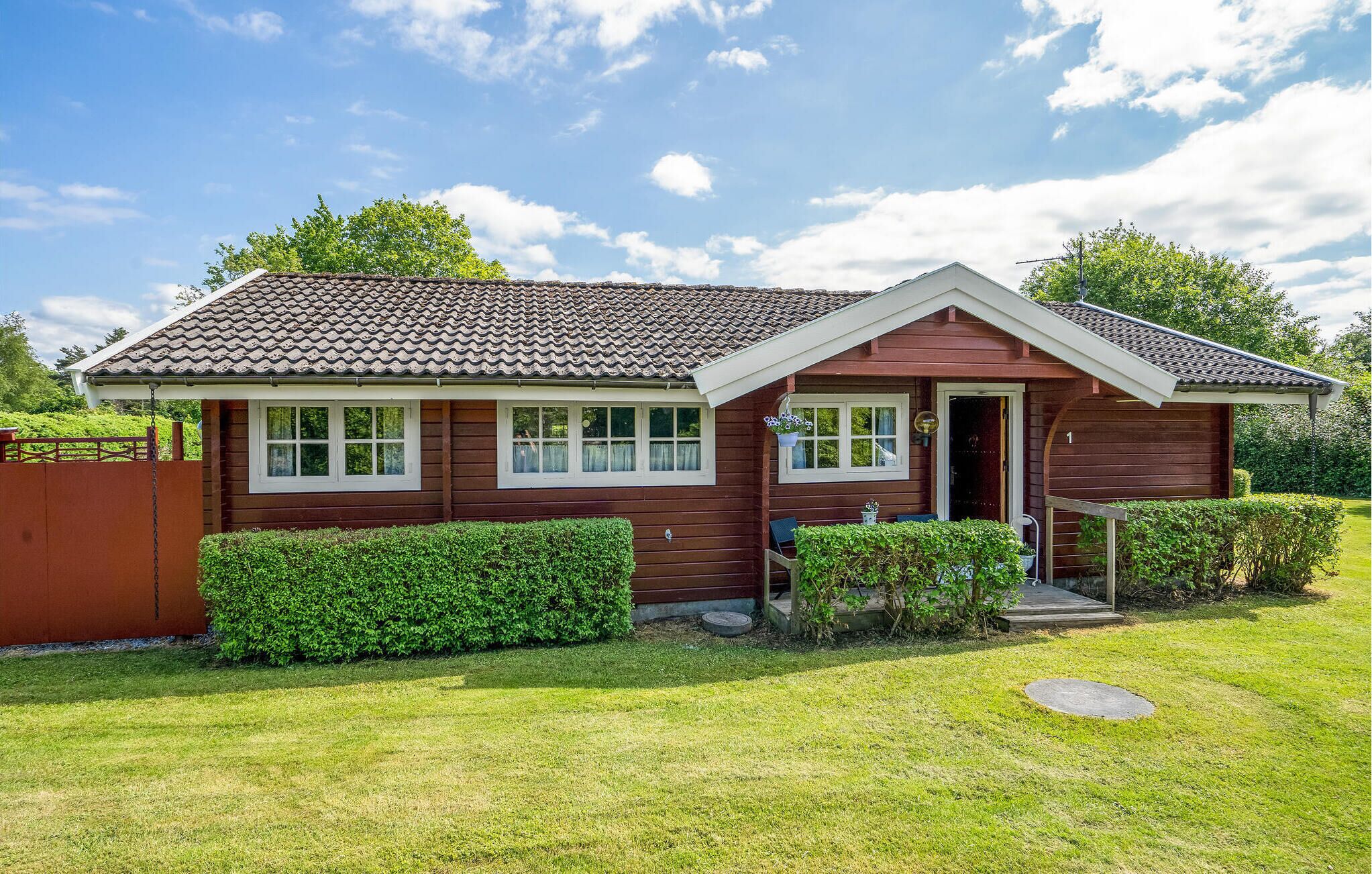 A single-story wooden house with a tiled roof, a front porch, and a well-maintained lawn.
