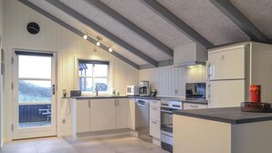 Eine moderne Küche mit weißen Schränken, einem eingebauten Backofen, einer Mikrowelle und einer Kaffeemaschine.