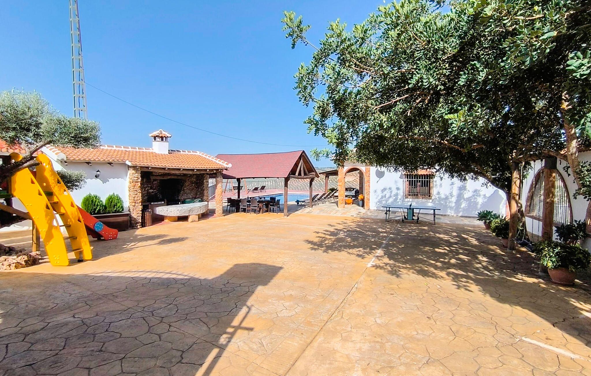 Ein Patio mit Steinboden, Sitzgelegenheiten im Freien und einer Spielanlage für Kinder.