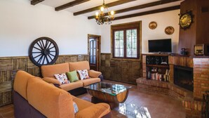 A cozy living room with a sofa, a coffee table, a TV, and a fireplace. - Beautiful home in Iznájar (Iznájar)