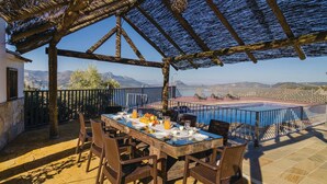 An outdoor dining area with a table set for two, overlooking a pool and mountains. - Beautiful home in Iznájar (Iznájar)
