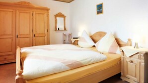 A bedroom with a bed, wooden wardrobe, and a nightstand. - Apartment E - Apartments Hasenpatt (Bad Sachsa)