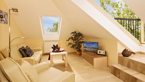 A modern loft apartment with a high ceiling, a dining area, a sofa, a TV, and a staircase.