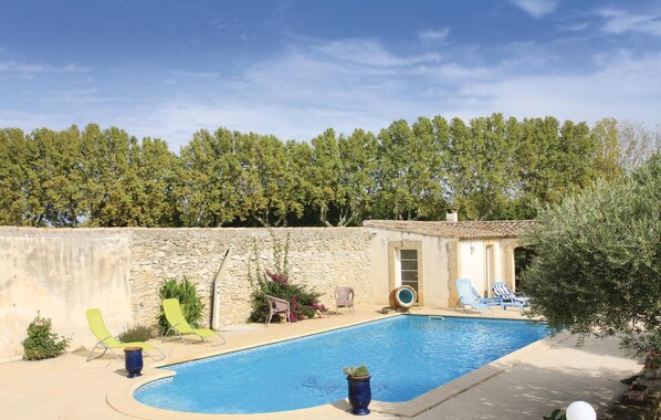 A swimming pool with lounge chairs and a stone wall.