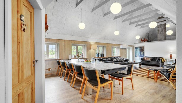 A spacious dining area with a long wooden table and chairs, large windows, and a high ceiling with exposed beams. - Stunning home in Ulfborg with sauna (Ulfborg)