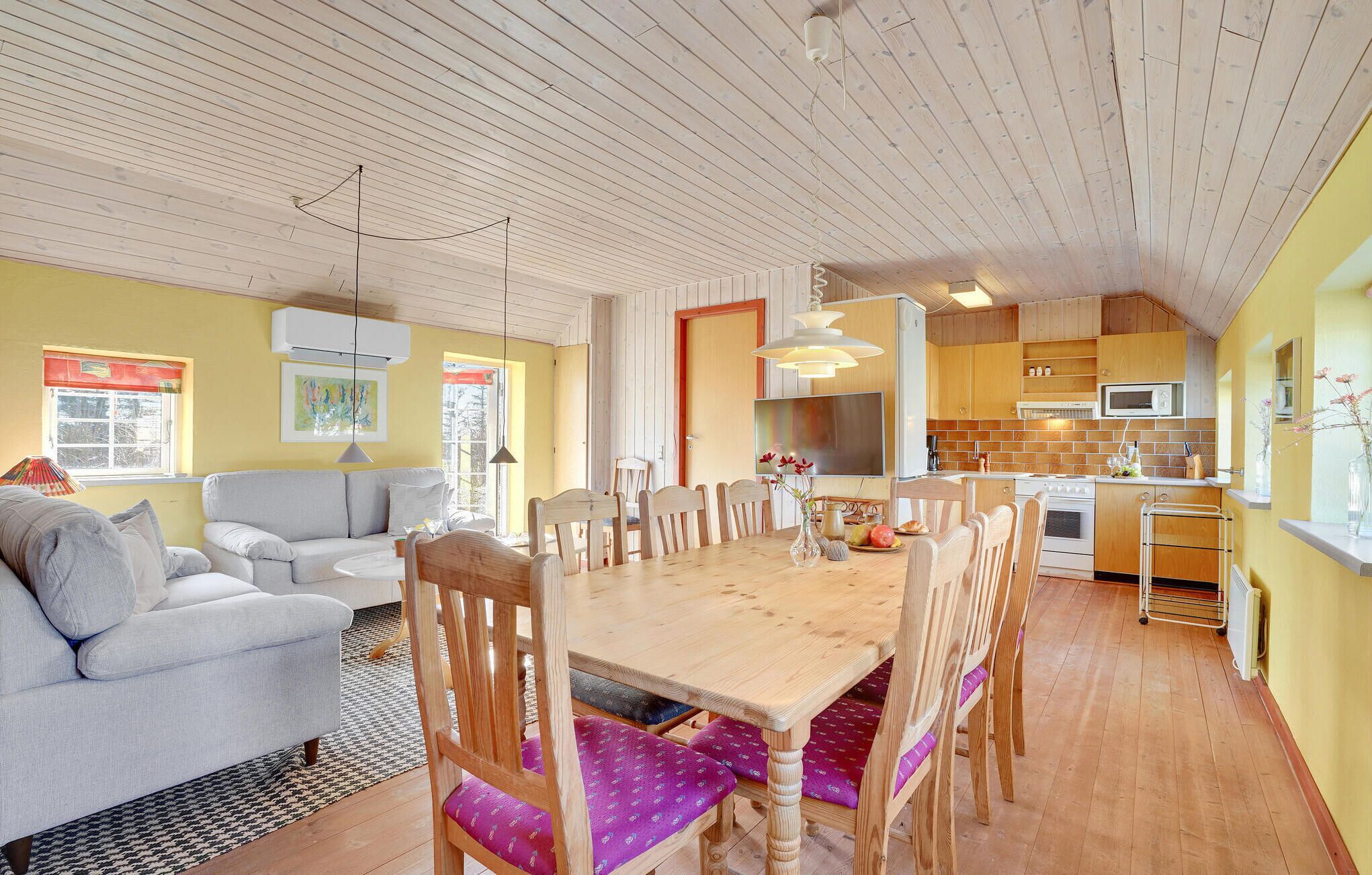 A cozy living room with a sofa and a dining table surrounded by chairs.