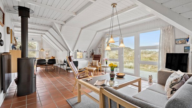 Ein großzügiger Wohnbereich mit hoher Decke, Kamin und großen Fenstern mit Blick ins Freie.