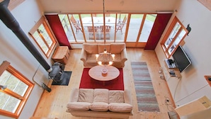 A cozy room with a sofa, a coffee table, and a TV. There are windows and a view of the outdoors. - Amazing home in Annerstad with sauna (Annerstad)