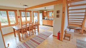 A spacious kitchen with wooden cabinets, a microwave, and a dining area with a table and chairs. - Amazing home in Annerstad with sauna (Annerstad)