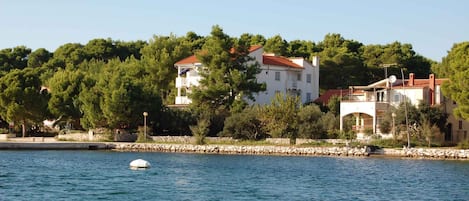 A coastal property with a stone wall and a boat in the water.