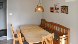 A dining area with a wooden table and benches, a hanging light fixture, and wall decorations.