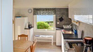 A compact kitchen with a dining area, a window with a view, and basic amenities.