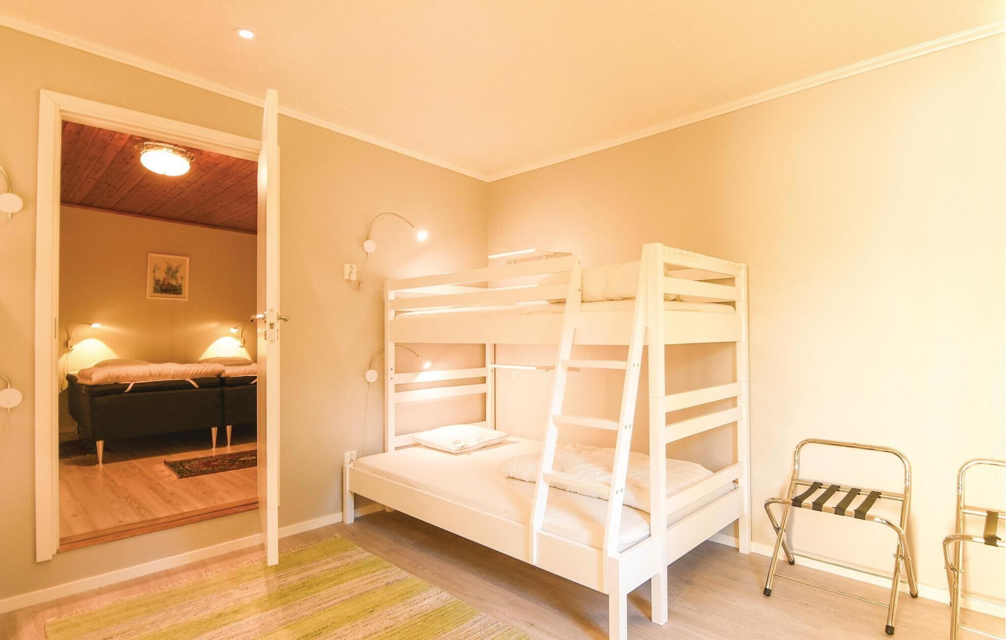 Une chambre avec un lit superposé, une porte donnant sur une autre pièce, une petite table et une chaise.