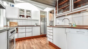 Una cucina moderna con mobili bianchi, un frigorifero in acciaio inossidabile e un piano di lavoro in legno.