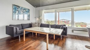 Un soggiorno moderno con un divano grigio, un tavolino in legno e un'ampia finestra che offre vista sulla città.