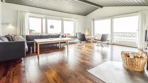 Un ampio soggiorno con soffitto in legno, ampie finestre, un divano, un tavolino da caffè e una TV.