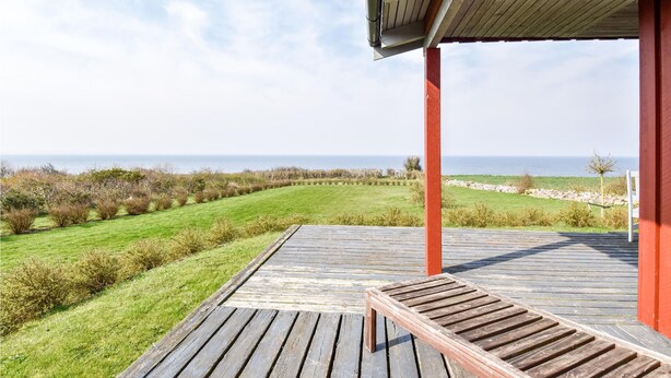 Un pontile in legno con una panchina, che si affaccia su un paesaggio erboso e il mare.