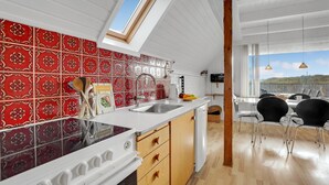 A modern kitchen with red patterned tiles, a skylight, and a dining area with a view. - Beach front home in Hvide Sande with WiFi (Hvide Sande)