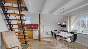 A modern kitchen with white cabinets, a red patterned backsplash, and a dining area with a white table and black chairs. - Beach front home in Hvide Sande with WiFi (Hvide Sande)