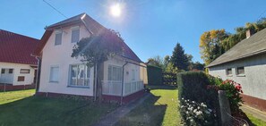 Ein zweistöckiges Haus mit rotem Dach und weißen Wänden, umgeben von einem gepflegten Rasen und einer Hecke.