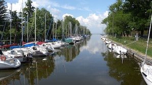 Ein Kanal gesäumt von Booten, Bäumen und einer entfernten Brücke.