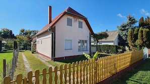 Ein einstöckiges Haus mit rotem Dach und weißen Außenwänden, umgeben von einem gelben Ziergarten und einem gepflegten Rasen.