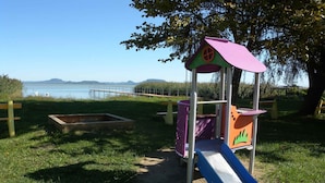 Ein Spielplatz mit Rutsche und Klettergerüsten in der Nähe von Wasser und einem Steg.