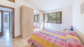 A bedroom with a large bed, a wardrobe, a window with a view of trees, and a door leading to a balcony. - 2 bedroom awesome home in Badesi OT (Badesi OT)