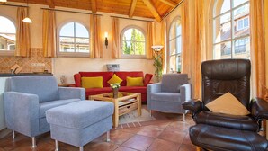 A spacious living area with a wooden ceiling, a red sofa with yellow cushions, a grey armchair, and a black leather chair. - L-39 - Residence Laguna Whg L-39 .. (Kühlungsborn)
