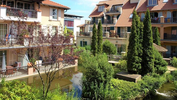 A residential building with multiple balconies, a pond, and surrounding greenery. - L-39 - Residence Laguna Whg L-39 .. (Kühlungsborn)