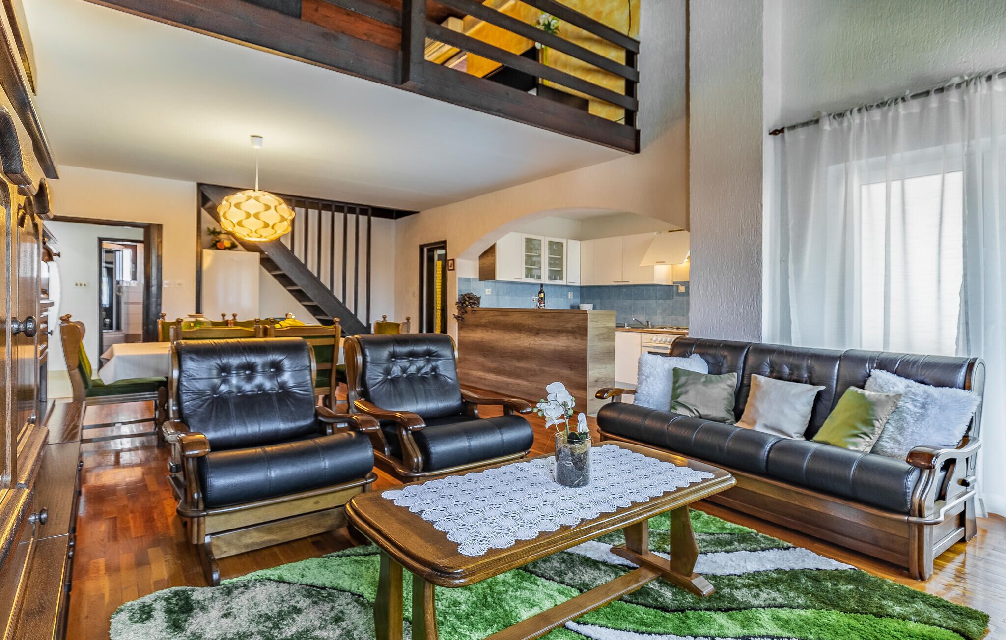 A spacious living room with leather sofas, a wooden coffee table, and a staircase leading to an upper level.