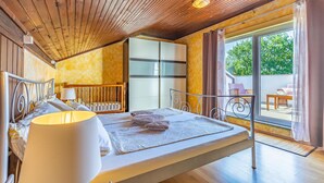 Een slaapkamer met een bed, nachtkastje, lamp, kast en uitzicht.