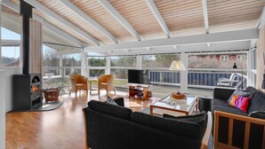 A spacious living area with a large wooden ceiling, a fireplace, and a view of a dock.