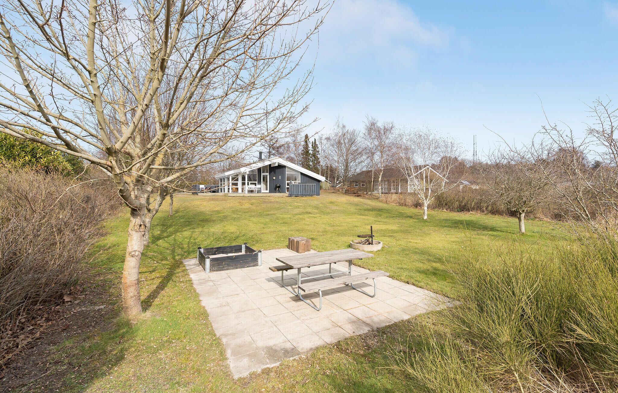 A modern house with a large deck and a fire pit.