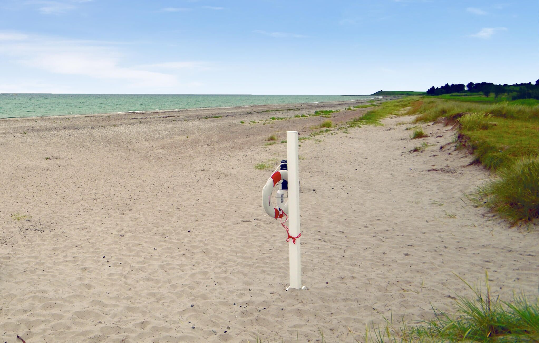 A sandy beach with a lifeguard tower and a clear view of the ocean.