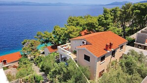 Un immobile costiero con tetto in tegole rosse, un piccolo balcone e vista mare.