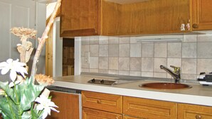 Keittiössä on puukuvioiset kaapit, valkoinen työtaso, pesuallas ja välitilan laatoitus.