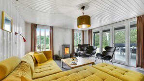 Ett modernt vardagsrum med en gul soffa, en öppen spis, en tv och en matplats med utsikt över utomhusområdet.